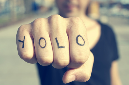 closeup of a young man with the word yolo, for you only live once, tattooed in his hand, with a filter effect